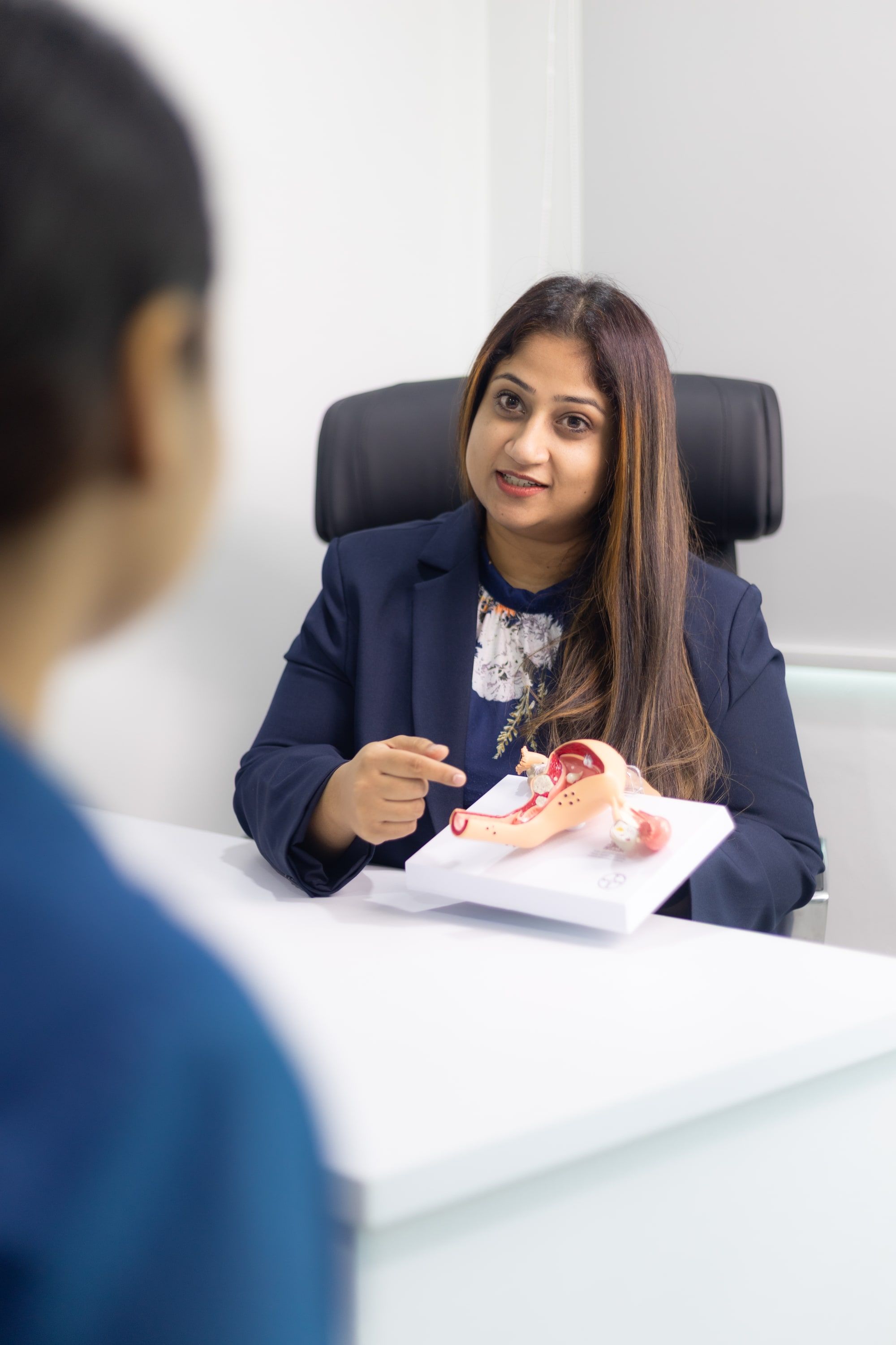 Dr Bheena Vyjhallaja pointing to an anatomical model of the uterus and ovaries on the desk while explaining it.